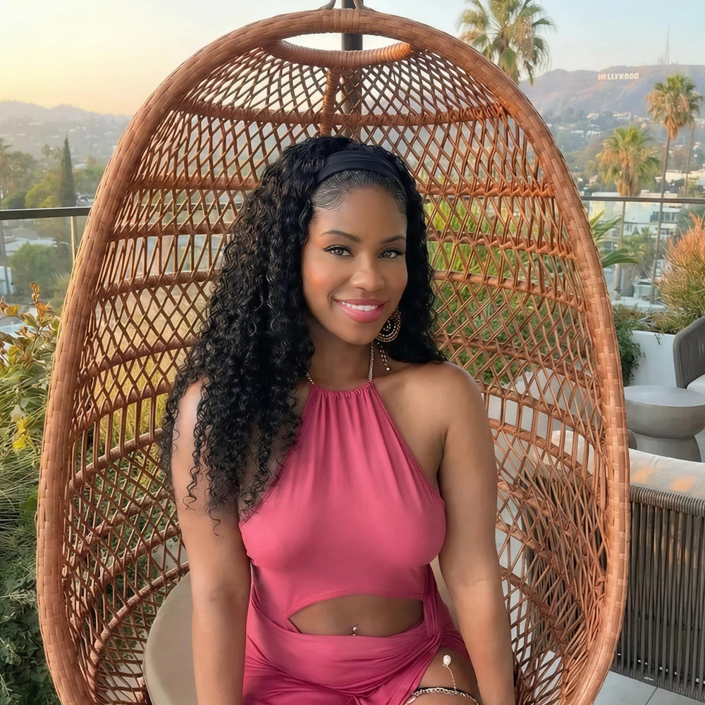 Mimicing Water Wave headband glueless wig styled on a model in a pink dress, featuring natural voluminous curls in a scenic outdoor setting.